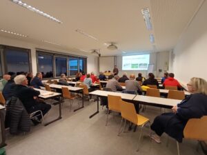 Ein Klassenraum besetzt mit Erwachsenen. Holger Langebröker hält ein Vortrag